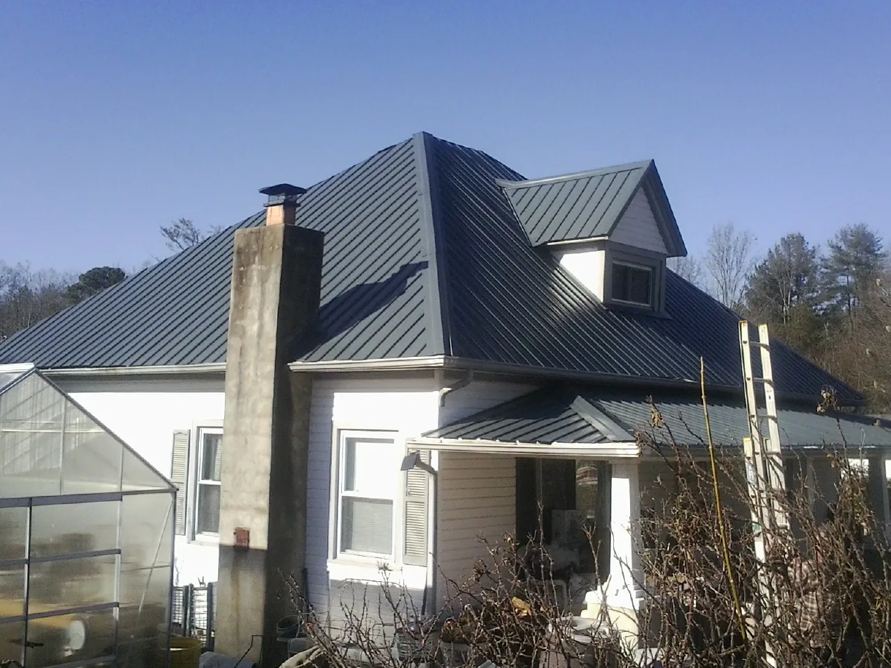 Dark blue standing seam metal roof on a white farmhouse with dormer — Slate & Tile Roof Repair by Roofing Brothers in Maynardville