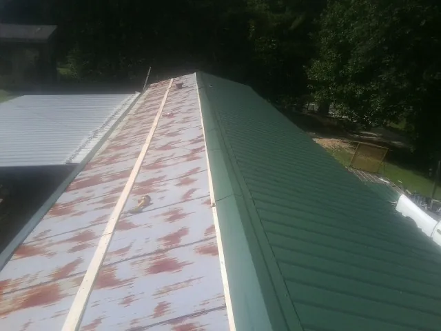 Old rusted panels beside newly installed green metal roofing — Wind Damage Roof Repair by Roofing Brothers in Maynardville