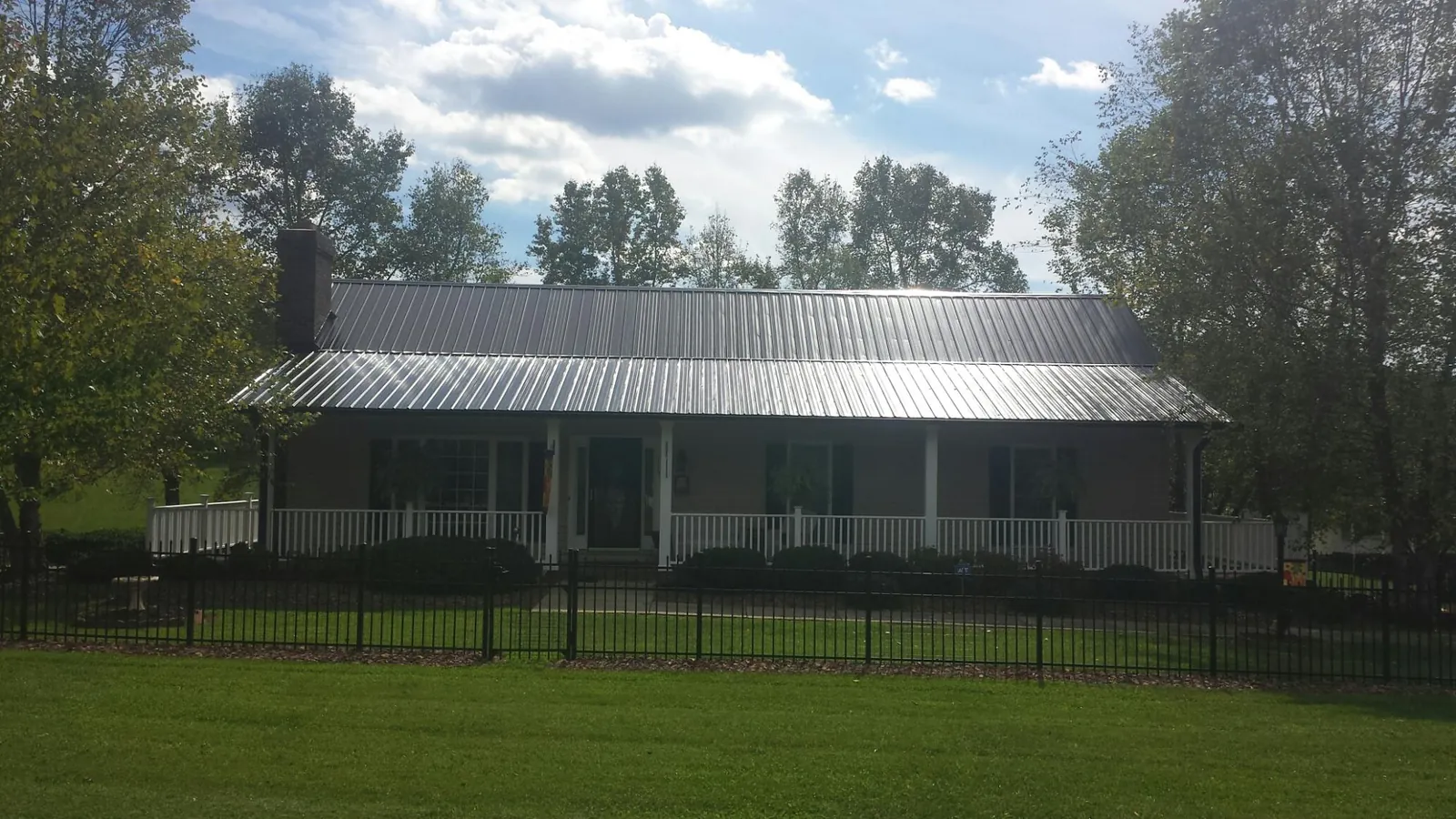 Gray metal roof on a brick ranch with a full width front porch — Gutter Guard Installation work by our crew in Maynardville