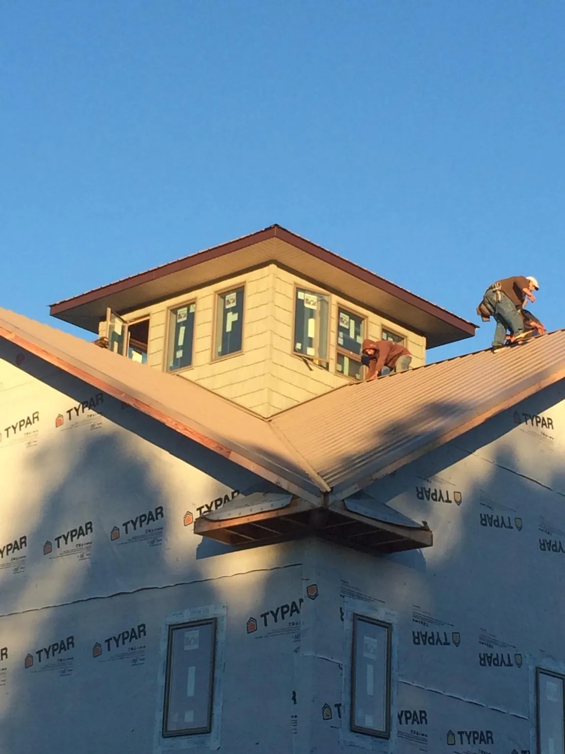 Roofers working around a rooftop cupola on a new metal roof at sunset — Roof Waterproofing in Maynardville by Roofing Brothers